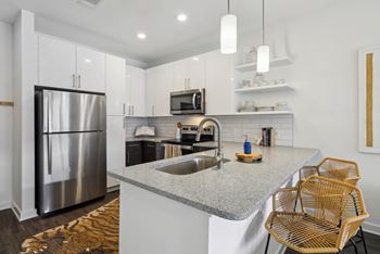 a kitchen with white cabinets and a granite counter top and a stainless steel refrigerator at Link Apartments® Broad Ave, Memphis